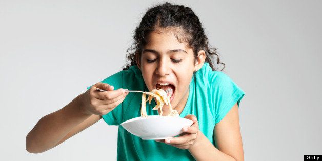 Girl (9-11) eating bowl of pasta