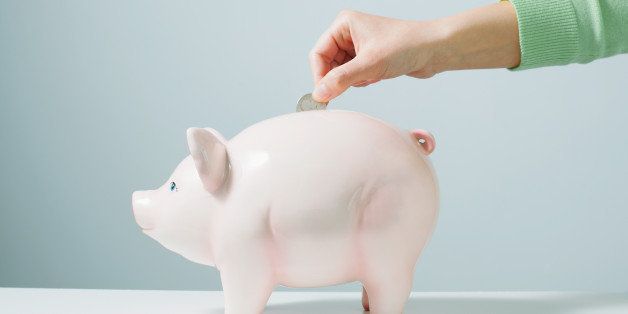 Woman's hand placing a coin into a piggy bank