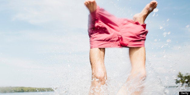 Man pulling off shorts in lake