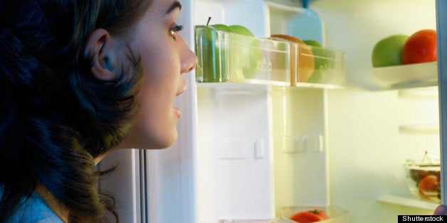 a hungry girl opens the fridge