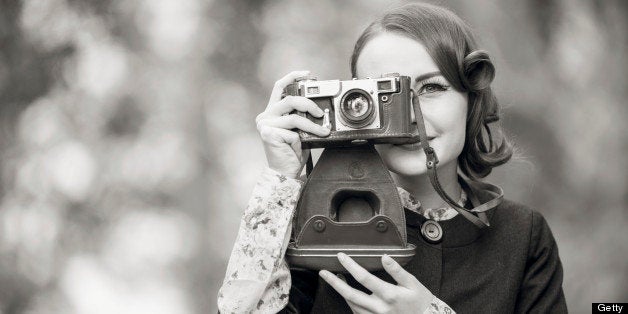 Retro style woman portrait outdoors using a vintage camera