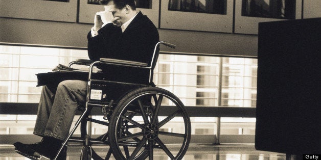 Businessman sitting in wheelchair at airport (B&W sepia tone)