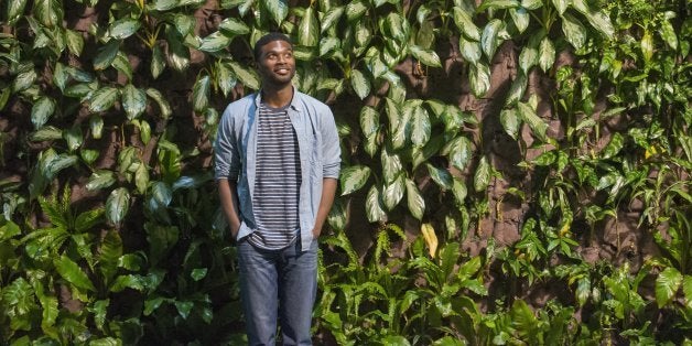 Outdoors in the city in spring. An urban lifestyle. A man looking up at a high wall covered in climbing plants and foliage.