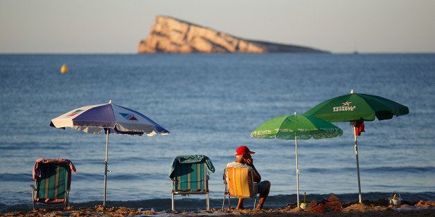 BENIDORM, SPAIN - AUGUST 10: A man sits on Levante Beach in the early morning on August 10, 2013 in Benidorm, Spain. Benidorm is one of Europe's top package holiday destinations and one of Spain's busiest tourist destinations. The Costa Blanca hotspot of Benidorm is calculated to have a population of around 72,000, which is estimated to rise to more than 300,000, during the summer months as the tourists and visitors flock to its popular beaches. (Photo by Pablo Blazquez Dominguez/Getty Images)