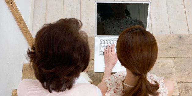 Mature woman and adult daughter sitting on stairs using laptop computer, overhead view