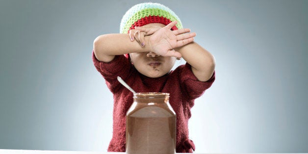 Little 4 years old girl embarrassed while eating her chocolate fudge