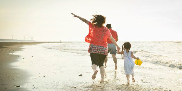 Family running on the beach happily