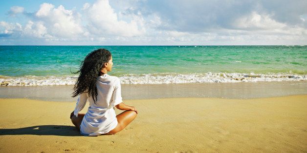Woman sitting on tropical beach looking out