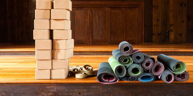 Yoga mats rolled up and ready for a class with a stack of blocks and straps. Colorful mats.