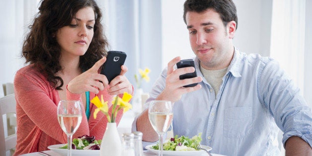 USA, New Jersey, Jersey City, Couple having dinner and text messaging