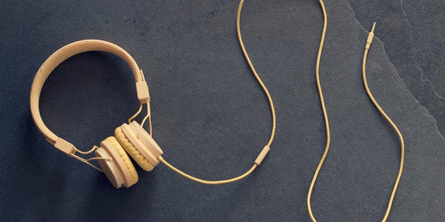 Yellow shoes and yellow headphones viewed from the top on a dark floor.