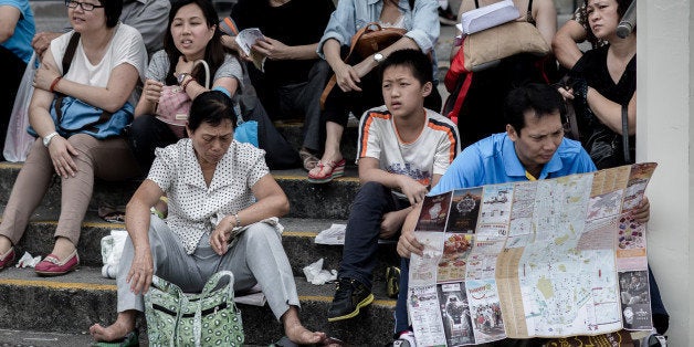 Chinese tourists visit a popular waterfront promenade in Hong Kong on October 2, 1013. China's National Tourism Administration publicised a 64-page Guidebook for Civilised Tourism -- with illustrations to accompany its list of dos and don'ts -- on its website ahead of a 'Golden Week' public holiday that started on October 1. AFP PHOTO / Philippe Lopez (Photo credit should read PHILIPPE LOPEZ/AFP/Getty Images)