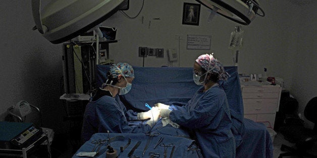 Colombian plastic surgeon Lina Triana (L) performs a breast augmentation surgery to Angie Astudillo in Cali, Valle del Cauca department, Colombia, on October 24, 2013. The city of Cali has become one of the favorite destinations for men and women from different countries who seek low cost cosmetic surgery performed with professionalism and experience. AFP PHOTO / Luis ROBAYO (Photo credit should read LUIS ROBAYO/AFP/Getty Images)