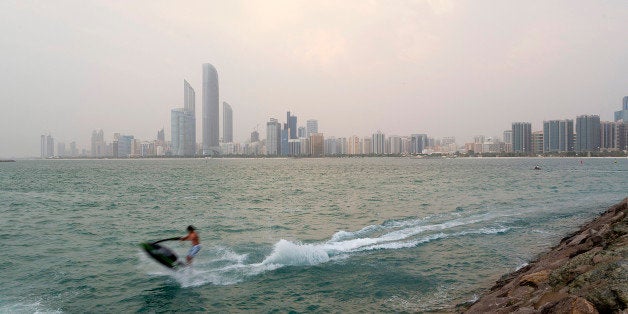 Skyscrapers stand on the city skyline beyond a jet skier passing close to the shore in Abu Dhabi, United Arab Emirates, on Mo