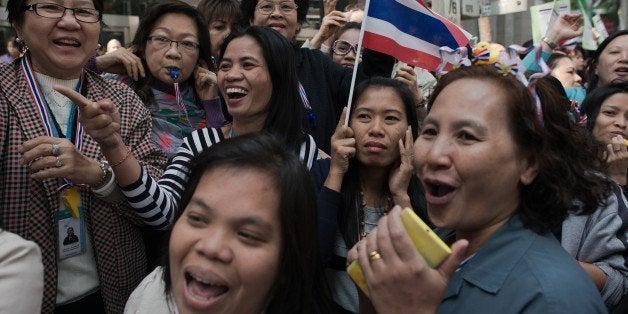 Thai anti-government protesters watch Thai protest leader Suthep Thaugsuban (not seen) as he marches in the streets during ongoing rallies in Bangkok on January 23, 2014. Defiant Thai opposition protesters vowed to ignore a state of emergency that came into force across the tense capital on January 22, refusing to abandon their fight to bring down the government. AFP PHOTO/ Nicolas ASFOURI (Photo credit should read NICOLAS ASFOURI/AFP/Getty Images)