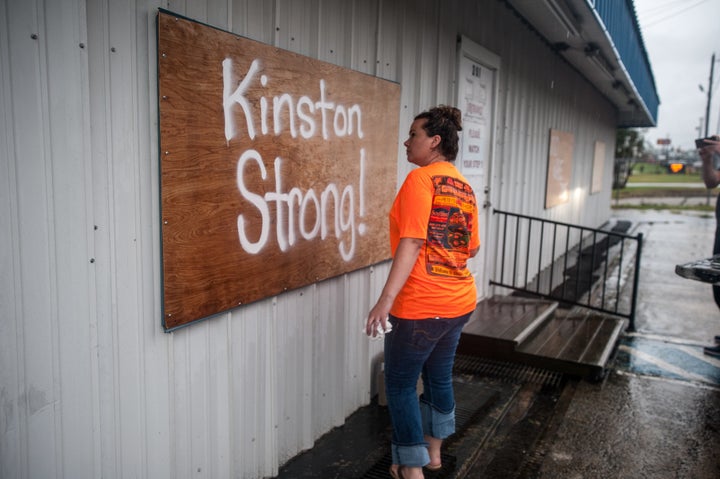 Rhoda Rikard paints "Kinston Strong!" on a board covering the window of her family business, Southland Flooring and Design, as she prepares against rising floodwaters from the Neuse River on Saturday.