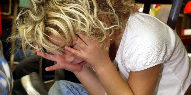 OAHU, HI - FEBRUARY 18: A kindergarten student hides under her desk during a classroom lockdown drill February 18, 2003 in Oahu, Hawaii. Lockdown procedure is used to protect school children from possible threats on campus such as intruders, terrorism or military attack. (Photo by Phil Mislinski/Getty Images)