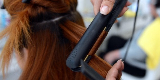 Hairdresser Arzu uses a hair straightener as she dresses a client's hair on August 8, 2012 at the Dry Bar in Berlin. The shop offers to make different blow-dried hairstyles, according to a new trend coming from the US. AFP PHOTO / BRITTA PEDERSEN GERMANY OUT (Photo credit should read BRITTA PEDERSEN/AFP/GettyImages)