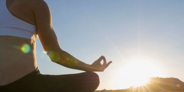 Woman sitting in lotus position at sunrise