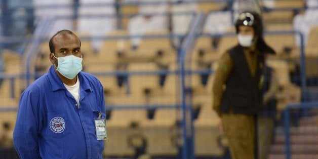 An Asian worker and Saudi policeman wear mouth and nose masks while they are on duty at the King Fahad stadium in Riyadh on April 22, 2014. The health ministry reported more MERS cases in Jeddah, prompting authorities to close the emergency department at the city's King Fahd Hospital. AFP PHOTO/FAYEZ NURELDINE (Photo credit should read FAYEZ NURELDINE/AFP/Getty Images)