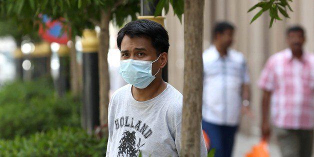 An Asian man wears a mouth and nose mask as he walks in a street of the Red Sea coastal city of Jeddah on April 27, 2014. The MERS death toll in Saudi Arabia neared 100 this weekend as the authorities scrambled to reassure an increasingly edgy population in the country worst-hit by the infectious coronavirus. AFP PHOTO/STR (Photo credit should read -/AFP/Getty Images)