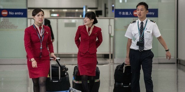 Flight attendants (L and C) for Cathay Pacific are seen arriving at the international airport in Hong Kong on May 5, 2014. Cathay Pacific flight attendants want the Hong Kong airline to redesign their uniforms because they are too revealing and may provoke sexual harassment, a union said on May 5. AFP PHOTO / Philippe Lopez (Photo credit should read PHILIPPE LOPEZ/AFP/Getty Images)