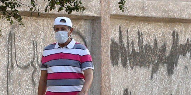 A saudi man wears wears a mouth and nose mask as he walks in a street of the Red Sea coastal city of Jeddah on April 27, 2014. The MERS death toll in Saudi Arabia neared 100 this weekend as the authorities scrambled to reassure an increasingly edgy population in the country worst-hit by the infectious coronavirus. AFP PHOTO/STR (Photo credit should read -/AFP/Getty Images)