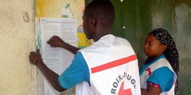 Members of the Guinean Red Cross stick information concerning the Ebola virus during an awareness campaign on April 11, 2014 in Conakry. Guinea has been hit by the most severe strain of the virus, known as Zaire Ebola, which has had a fatality rate of up to 90 percent in past outbreaks, and for which there is no vaccine, cure or even specific treatment. The World Health Organization (WHO) has described west Africa's first outbreak among humans as one of the most challenging since the virus emerged in 1976 in what is now the Democratic Republic of Congo. AFP PHOTO / CELLOU BINANI (Photo credit should read CELLOU BINANI/AFP/Getty Images)