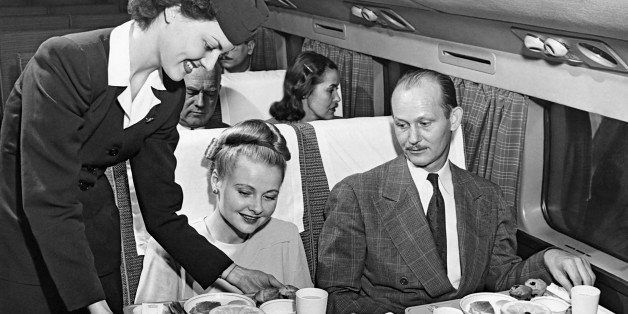 A stewardess serves a meal to a couple on an American Airlines flight, mid to late 1950s. (Photo by Underwood Archives/Getty Images)
