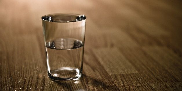 Half-filled glass of water on table.
