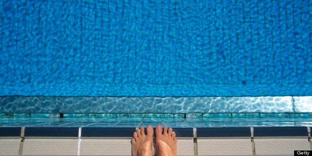 Feet at edge of swimming pool, elevated view