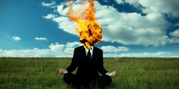 Businessman with burning box on the head, against meadow