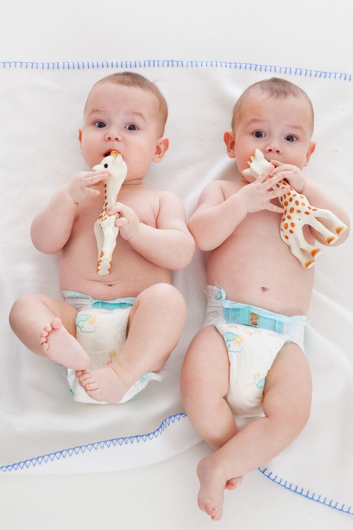 two babies wear diapers and lie on a blanket
