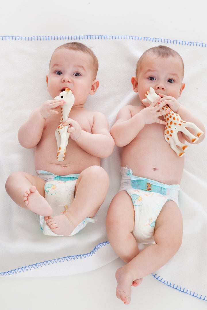 two babies wear diapers and lie on a blanket