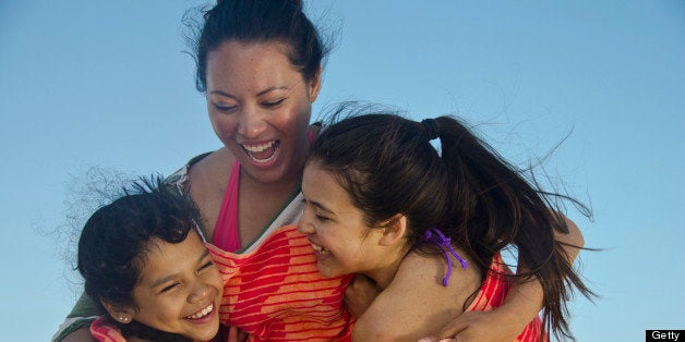 Mom having fun with her two daughters on the beach