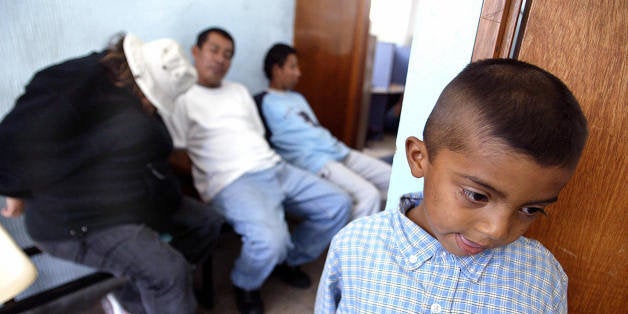 SAN SALVADOR, EL SALVADOR: Marvin Cristino Ventura(R) who is 7 years old, waits in a Police Border Station near of US citizen Heather Livengood Mc Clung (L) and Salvadoreans Humberto Ibarra (C) and Juan Moran (R) on February 10, 2004. The three last ones were arrested accused of people traffic when they were carrying five Salvadorean children to their families in the United States. AFP PHOTO/ Yuri CORTEZ (Photo credit should read YURI CORTEZ/AFP/Getty Images)