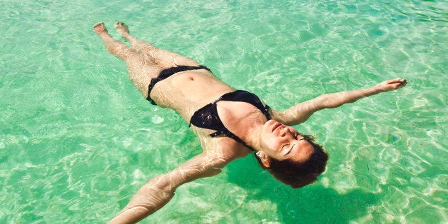 Young woman floating and relaxing backstroke in tropical water of Caribbean, St. Thomas U.S. Virgin Islands.