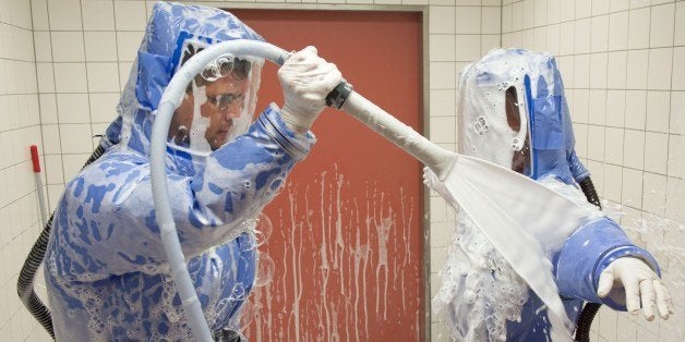 Infectious disease specialist Florian Steiner (L) and quarantine office leader Thomas Klotzkowski disinfect themselves during a demonstration of the proceedings at the ward of Berlin's Charite hospital on August 11, 2014. The quarantine ward is prepared to receive persons sick with tropical diseases, like people infected with the deadly Ebola virus for example. AFP PHOTO / DPA / TIM BRAKEMEIER / GERMANY OUT (Photo credit should read TIM BRAKEMEIER/AFP/Getty Images)