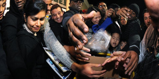 Best Buy bargain hunters swarm manager Ramon Estevez as he hands out scarves and hats that will identify those eligible for specially priced door buster sale items late in the evening on Thanksgiving Day, Thursday, Nov. 28, 2013, in Dunwoody, Ga. Instead of waiting for Black Friday, which is typically the year's biggest shopping day, more than a dozen major retailers opened on Thanksgiving this year. (AP Photo/David Tulis)