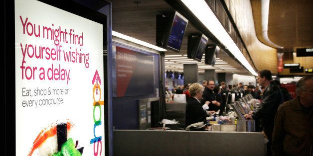 A sign promoting shopping and dining at Seattle-Tacoma International Airport is shown as workers at a Delta Air Lines ticket counter work to re-book customers who were scheduled to fly on delayed or canceled flights out of Seattle-Tacoma International Airport, Thursday, Jan. 19, 2012, in Seattle. On the heels of heavy snow that fell Wednesday, the Western Washington region was hit with an ice storm Thursday that closed runways at the airport and stranded hundreds of travelers. (AP Photo/Ted S. Warren)