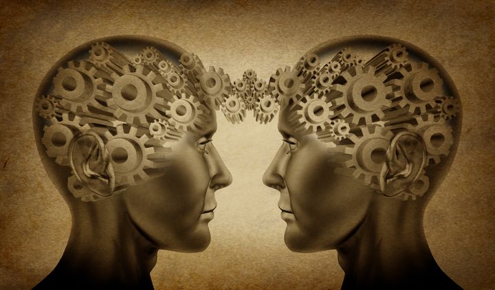 Business partnership and teamwork symbol represented by two human heads with gears connected together as a symbol of network referrals and relationships on an old grunge parchment background.