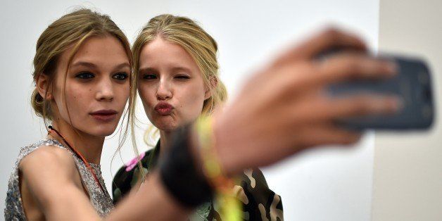 Models pose for a selfie backstage prior the Blugirl collection show during the 2015 Spring / Summer Milan Fashion Week on September 18, 2014 in Milan. AFP PHOTO / GABRIEL BOUYS (Photo credit should read GABRIEL BOUYS/AFP/Getty Images)