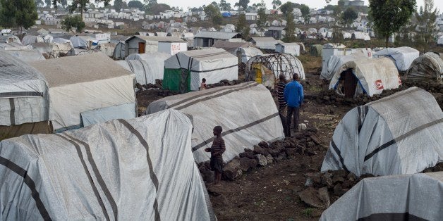 Displaced Congolese stand near makeshift shelters on July 14, 2014 at the Bulengo camp for internally displaced persons (IDPs), 20 kms west of Goma in the east of the Democratic Republic of the Congo. Over 55,000 people, fleeing violence in North Kivu province, live in the makeshift camp, made of basic huts, where many people complain of a lack of assistance from the humanitarian community. Food deliveries are targeting only people considered 'the most vulnerable'. AFP PHOTO/PHIL MOORE (Photo credit should read PHIL MOORE/AFP/Getty Images)