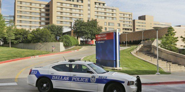 A police car drives past the entrance to the Texas Health Presbyterian Hospital in Dallas, Tuesday, Sept. 30, 2014. A patient in the hospital is showing signs of the Ebola virus and is being kept in strict isolation with test results pending, hospital officials said Monday. (AP Photo/LM Otero)
