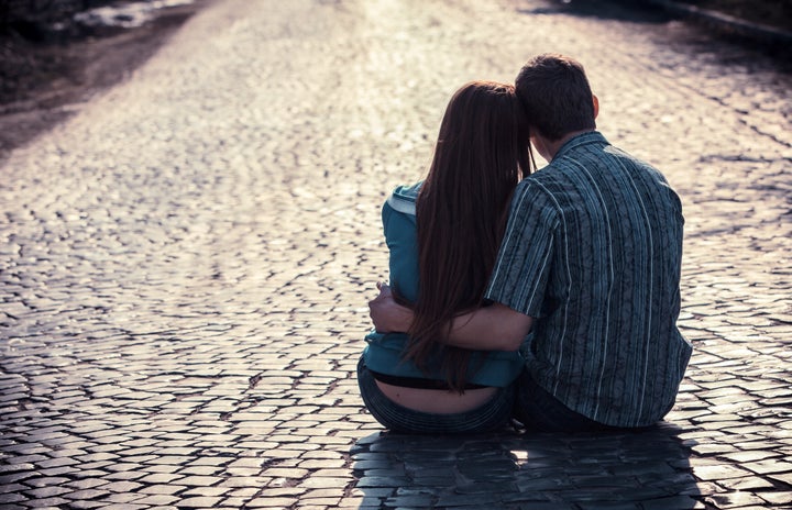 Couple of teenagers sit in street together