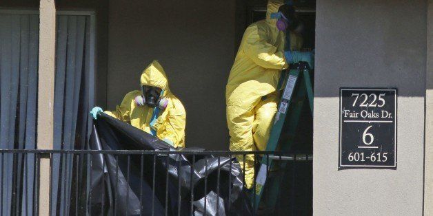 Hazardous material cleaners prepare to hang black plastic outside the apartment in Dallas, Friday, Oct. 3, 2014, where Thomas Eric Duncan, the Ebola patient who traveled from Liberia to Dallas stayed last week. The crew is expected to remove items including towels and bed sheets used by Duncan, who is being treated at an isolation unit at a Dallas hospital. The family living there has been confined under armed guard while being monitored by health officials. (AP Photo/LM Otero)