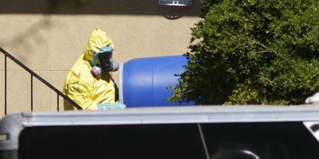 A hazardous material cleaner removes a blue barrel from the apartment in Dallas, Friday, Oct. 3, 2014, where Thomas Eric Duncan, the Ebola patient who traveled from Liberia to Dallas stayed last week. The family living there has been confined under armed guard while being monitored by health officials. (AP Photo/LM Otero)