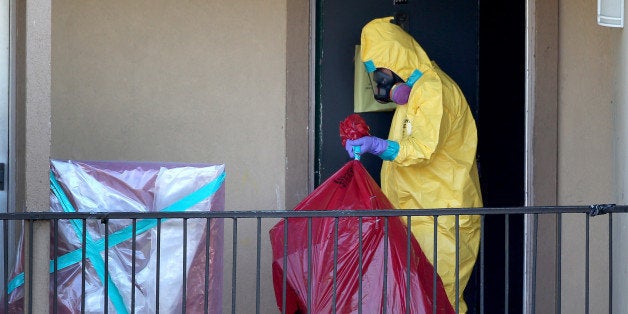 DALLAS, TX - OCTOBER 06: A member of the Cleaning Guys Haz Mat clean up company removes items from the apartment where Ebola patient Thomas Eric Duncan was staying before being admitted to a hospital on October 6, 2014 in Dallas, Texas. The first confirmed Ebola virus patient in the United States was staying with family members at The Ivy Apartment complex before being treated at Texas Health Presbyterian Hospital Dallas. State and local officials are working with federal officials to monitor other individuals that had contact with the confirmed patient. (Photo by Joe Raedle/Getty Images)