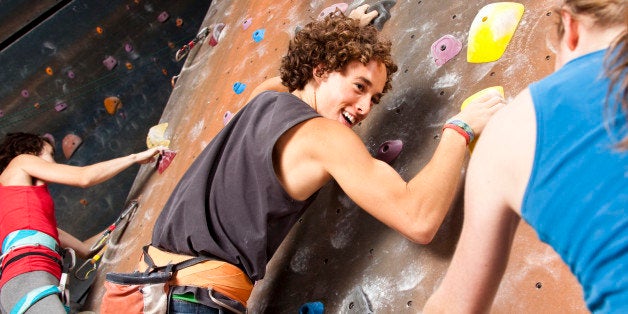 Three happy teenagers having fun at rock climbing wall