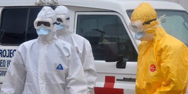 Health workers in protective gear wait to carry a body of a person suspected to have died from Ebola not in frame Monrovia ,Liberia. Monday, Oct. 13, 2014. Some nurses in Liberia defied calls for a strike on Monday and turned up for work at hospitals amid the worst Ebola outbreak in history. In view of the danger of their work, members of the National Health Workers Association are demanding higher monthly hazard pay. The association has more than 10,000 members, though the health ministry says only about 1,000 of those are employed at sites receiving Ebola patients. (AP Photo/ Abbas Dulleh)